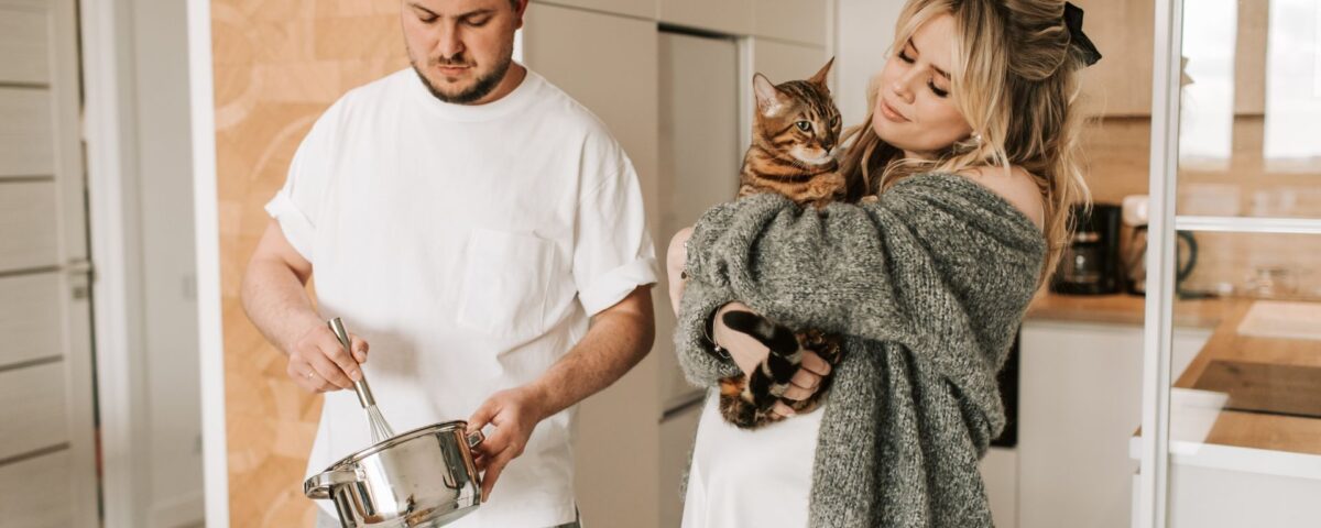 Couple in the kitchen, one of them is holding a cat