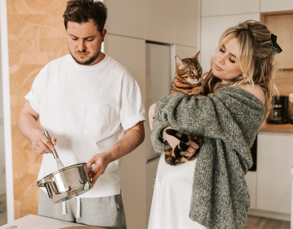 Couple in the kitchen, one of them is holding a cat
